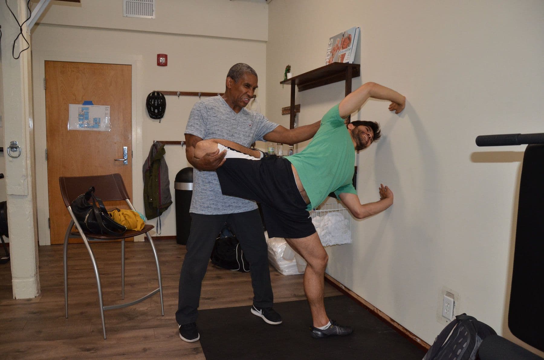 Bill supporting a client in a full-body stretch against the studio wall